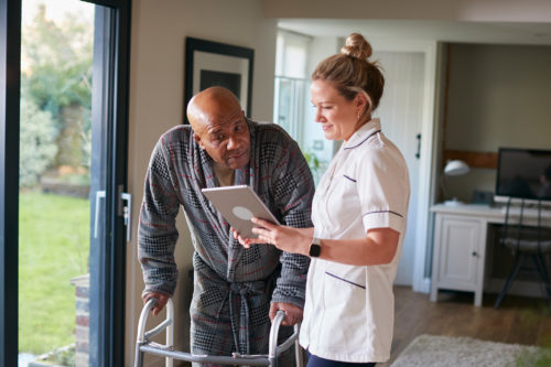 Medical staff from Harford Belair helps a senior male rehabilitation client using a walker.